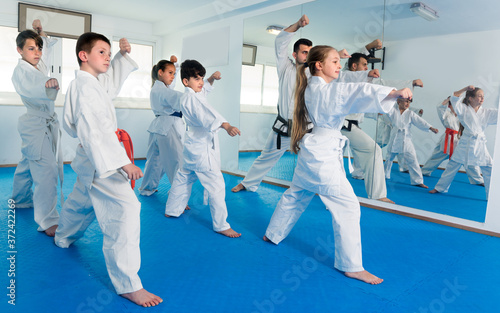 Children are practicing new moves by repeating for the trainer in karate class.