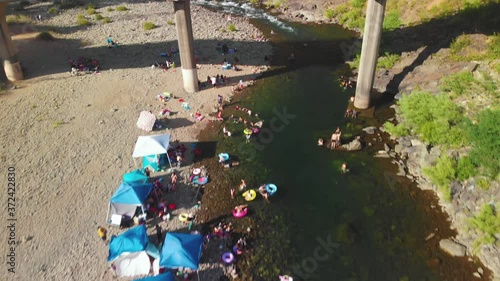 Close up view of a bridge crossing over the Auburn swimming hole on the American River in California - surrounded by green trees and filled with people swimming and enjoying their summer weekend photo