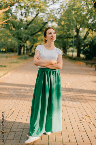 Photos A young beautiful girl in a white T-shirt and a long green skirt went for a walk
