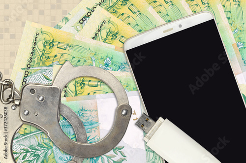 50 Belorussian rubles bills and smartphone with police handcuffs. Concept of hackers phishing attacks, illegal scam or malware soft distribution photo
