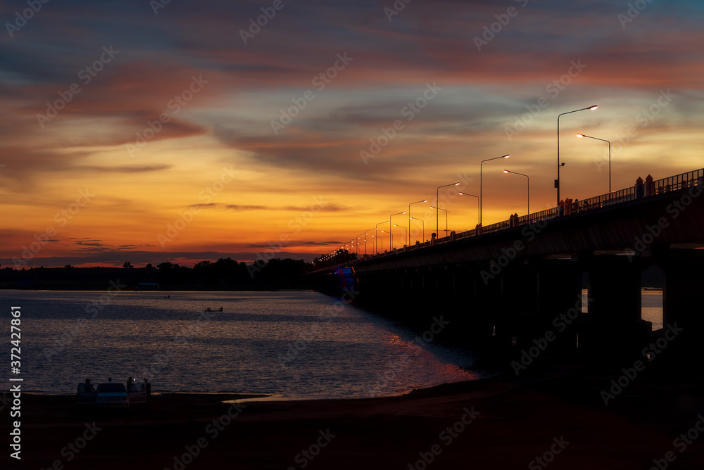 Silhouette of a bridge stretching across a twilight river at Lam Pao Dam, Kalasin Province, Thailand