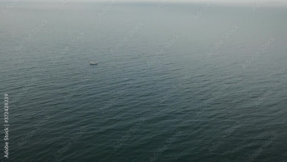 Super wide high aerial view of small sailboat in middle of vast sea Super wide high aerial view of small sailboat in middle of vast sea