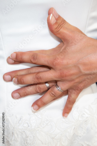 Wedding rings and couple hands bride and groom in love over marriage dress