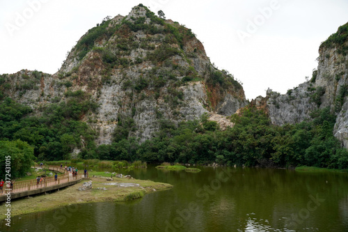 Beautiful range of rocks mountain with many tourist coming and sightseeing around pond or lake along the way to the mountain at Kuao Hin Ngu public park in Ratchaburi province  Thailand