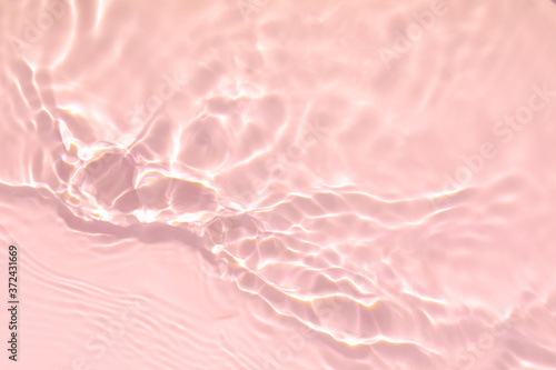 Closeup of pink transparent clear calm water surface texture with splashes and bubbles. Trendy abstract summer nature background. Coral colored waves in sunlight. photo