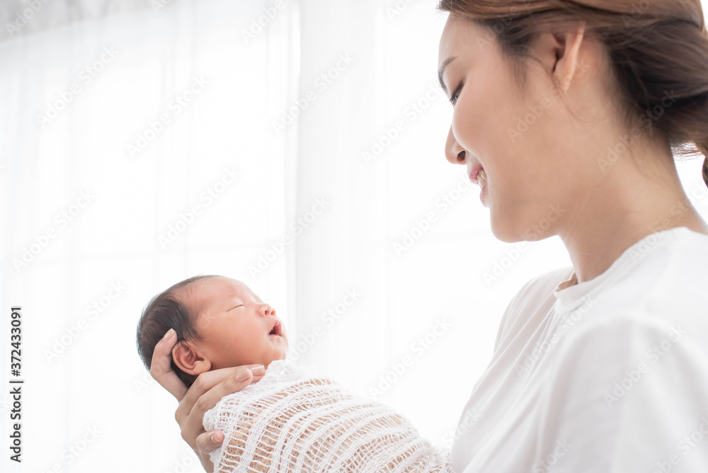 Pretty woman holding a newborn baby in her arms. happy loving family. mother playing with her baby in the bedroom. Pretty woman holding a newborn baby in her arms. happy loving family. mother playing with her baby in the bedroom.