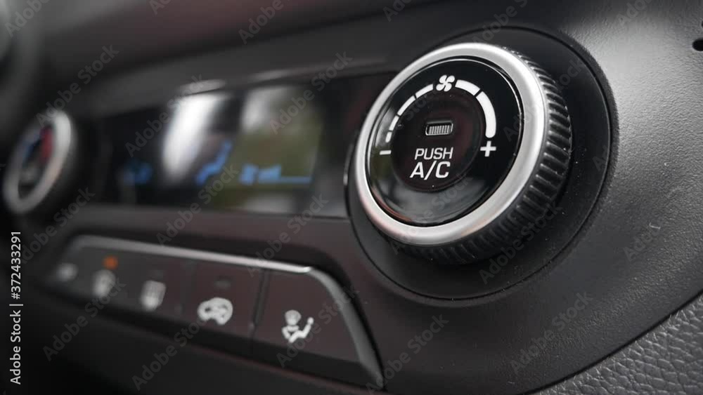 Close-up of pushing a button to turn off the air conditioner in a car. The mans hand turns the button