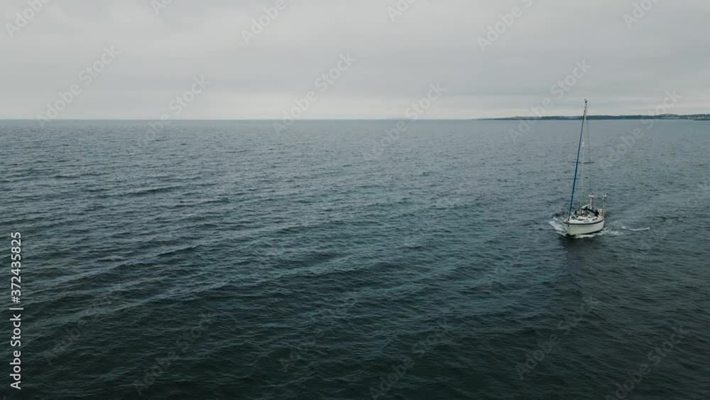Low rotating aerial shot of sailboat sailing through open water Low rotating aerial shot of sailboat sailing through open water