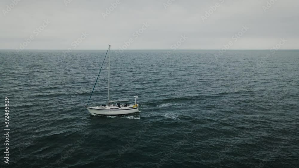 Low angle aerial passing by sailboat at sea Low angle aerial passing by sailboat at sea
