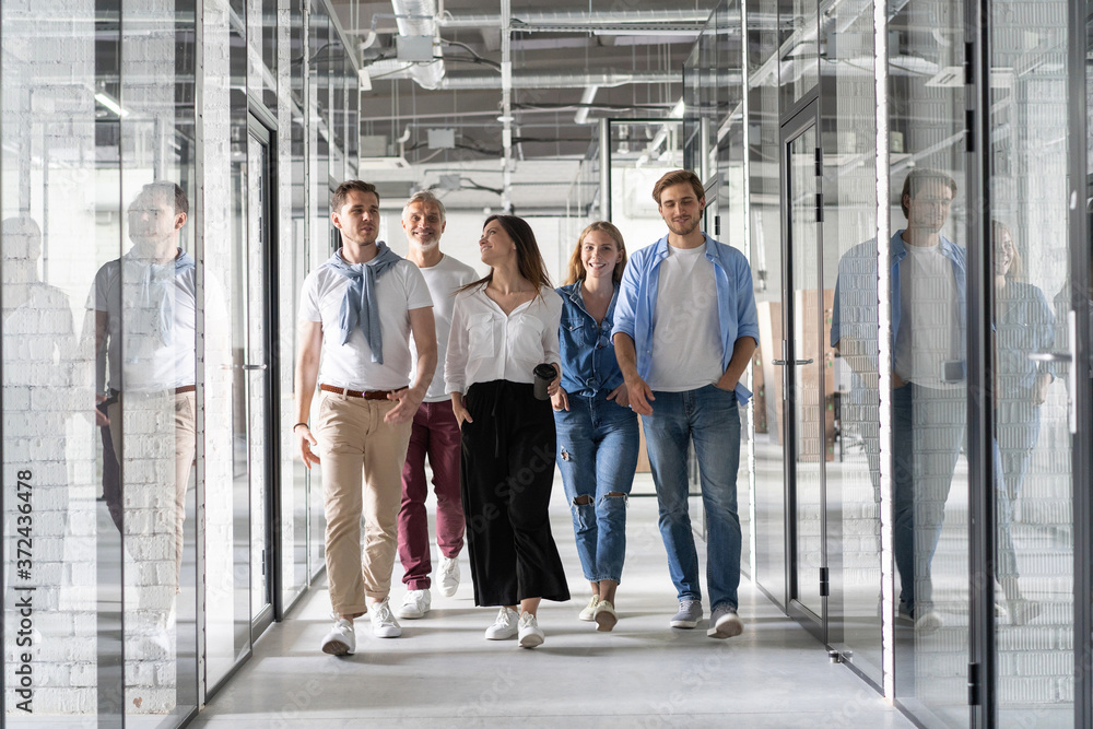 Obraz premium On the way to business meeting. Full length of young modern people in smart casual wear having a discussion while walking through the office