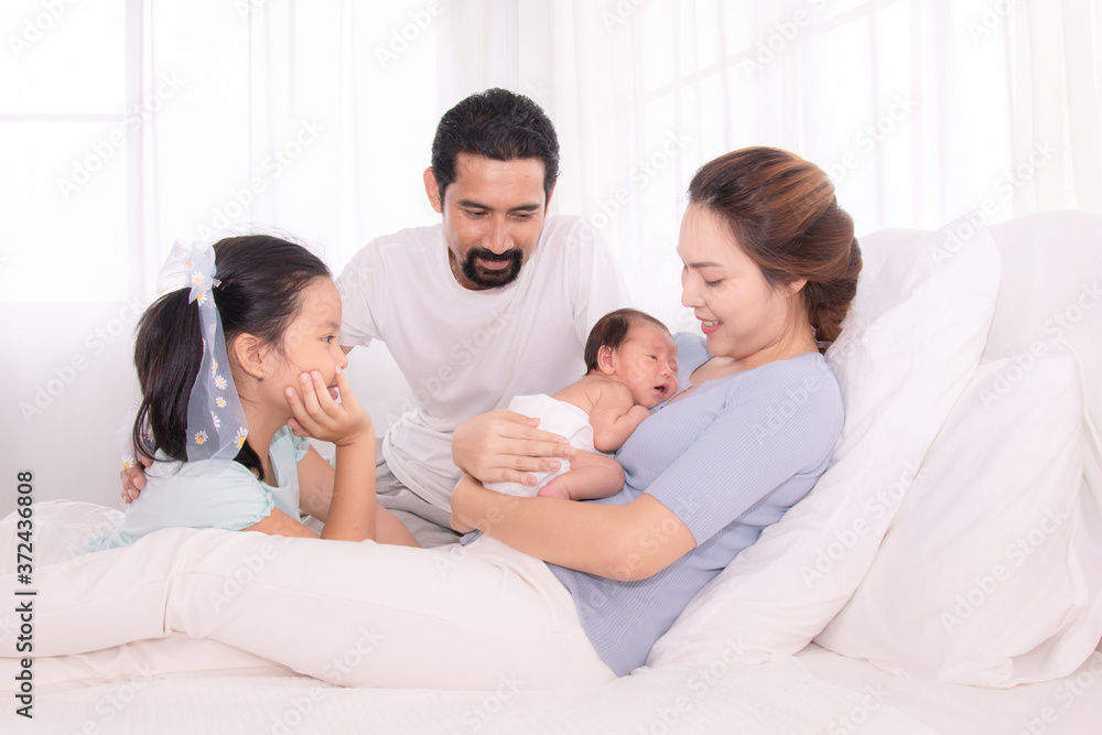 Happy family concept, father and daughter sit on bed excited looking new member in family, adorable newborn sleep on mother chest, mom hold infant embracing and caring while look daughter with love Happy family concept, father and daughter sit on bed excited looking new member in family, adorable newborn sleep on mother chest, mom hold infant embracing and caring while look daughter with love