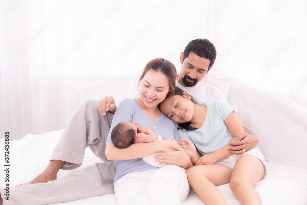 Happy family concept, father and daughter sit on bed excited looking new member in family, adorable newborn sleep on mother chest, mom hold infant embracing and caring while look daughter with love Happy family concept, father and daughter sit on bed excited looking new member in family, adorable newborn sleep on mother chest, mom hold infant embracing and caring while look daughter with love