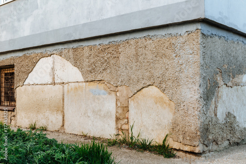 Fototapeta Naklejka Na Ścianę i Meble -  Plaster peeling off brick wall. The foundation of a residential building is gradually collapsing