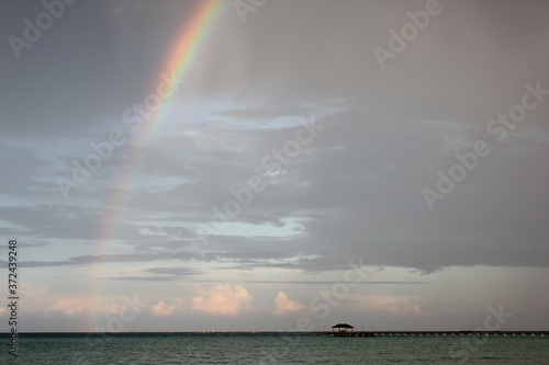 rainbow in the sky sea with a building on the horizon