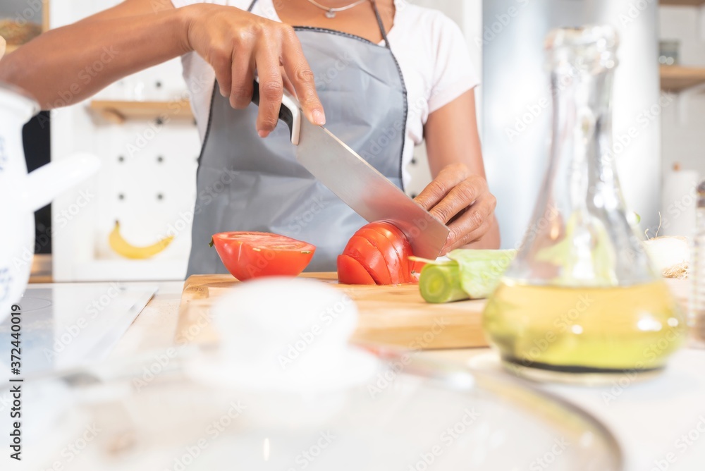 Woman chopping tomatoes in domestic kitchen