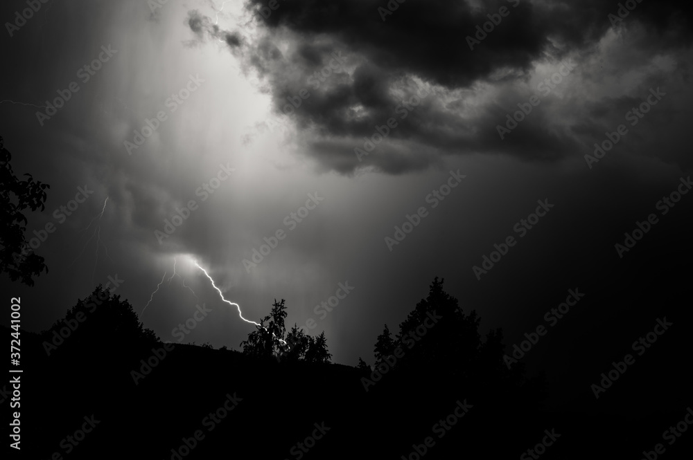 Fototapeta premium Lightning storm at night over dark landscape