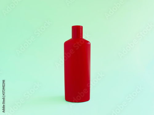 Mockup of unbranded red plastic bottle on green background. Cosmetic bottle container for branding of medicine or cosmetics. Natural organic spa cosmetics concept.