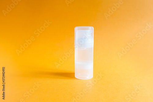 Mockup of transparent bottle of intimate lubricant gel on a textured bright orange background. Bottle for branding and label.