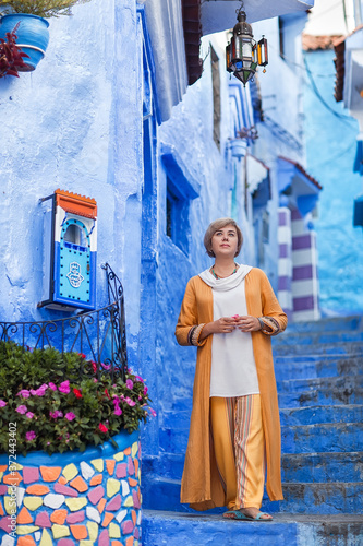 Lady in orange walks in a blue city © Marina