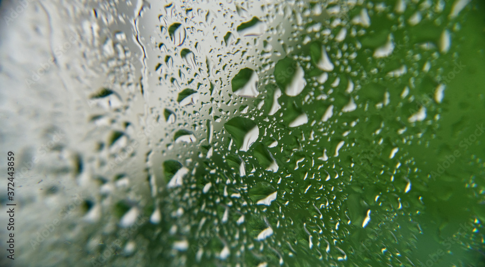 Heavy rainfall / raindrops on a window looking out to a mostly green garden Heavy rainfall / raindrops on a window looking out to a mostly green garden