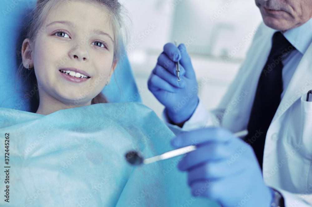 Naklejka premium Little girl sitting in the dentists office
