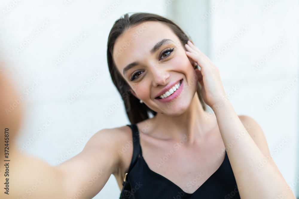 Fototapeta premium Young and beautiful. Pretty girl making selfie while having a walk around the city