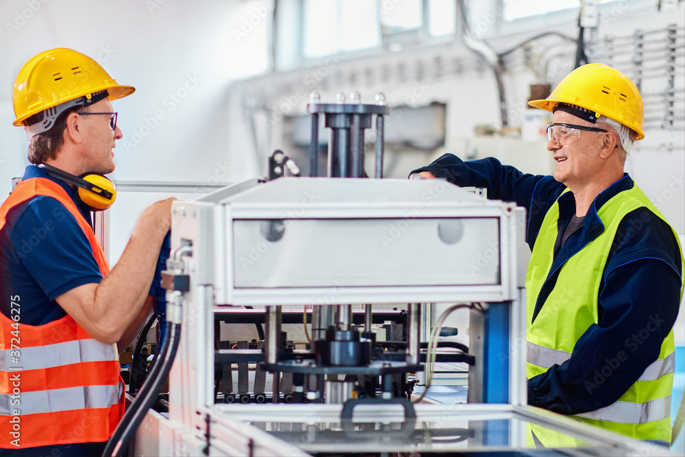 Men working in a industrial factory, wearing protective wear Men working in a industrial factory, wearing protective wear