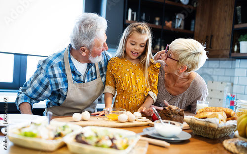 Smiling grandparents having breakfast with their granddaughter