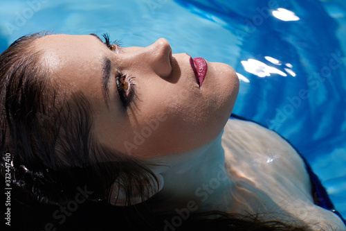 Close up portrait of beautiful woman in water with make up .
