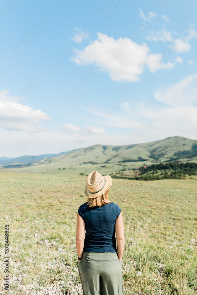 Young female nature lover enjoying the view of a mountain range in summertime
