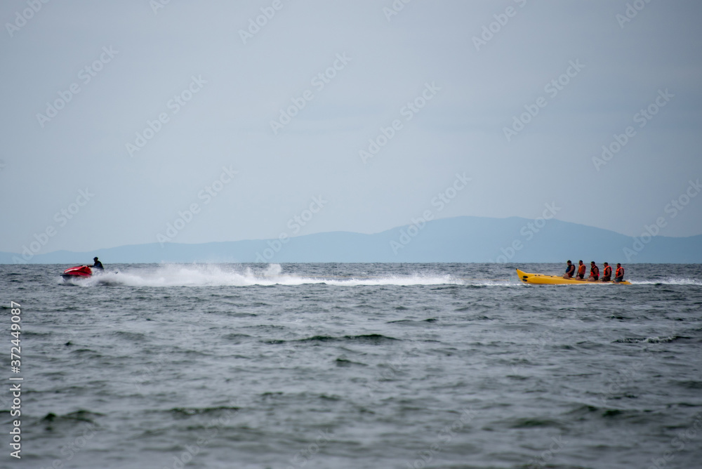 people having fun on holiday in the sea, and ride on an inflatable boat and a water motorcycle