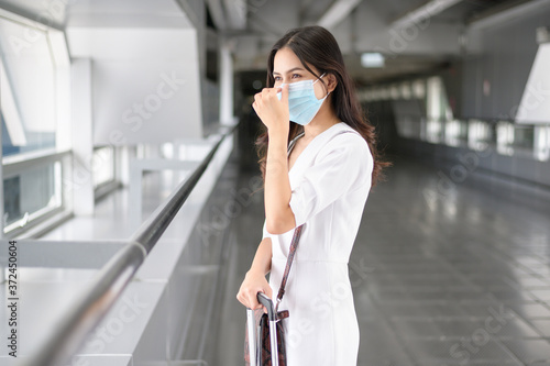 A traveller woman is wearing protective mask in International airport, travel under Covid-19 pandemic, safety travels, social distancing protocol, New normal travel concept