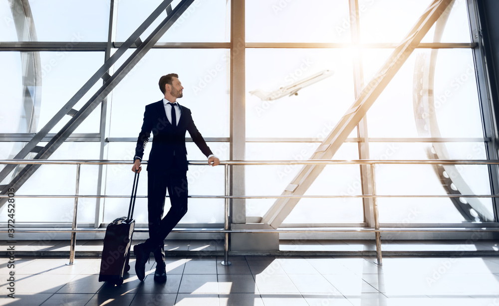 Excited businessman standing next to window at airport Excited businessman standing next to window at airport