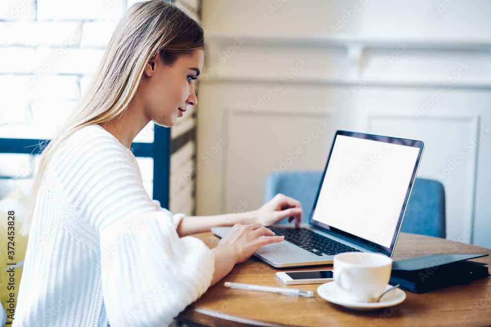 Skilled female freelancer working remotely at modern laptop computer with blank screen area for IT advertising, side view of woman typing mock up text on copy space netbook using 4g wireless Skilled female freelancer working remotely at modern laptop computer with blank screen area for IT advertising, side view of woman typing mock up text on copy space netbook using 4g wireless
