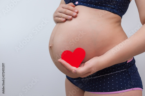 Wallpaper Mural A pregnant woman holds a heart symbol against the background of her stomach Torontodigital.ca