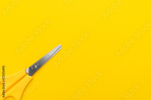 Yellow scissors on yellow background. Flat lay image of scissors with copy space.