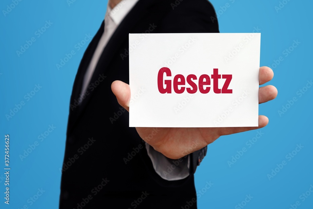 Gesetz. Geschäftsmann im Anzug zeigt Karte mit Text. Mann isoliert vor Hintergrund (blau) Gesetz. Geschäftsmann im Anzug zeigt Karte mit Text. Mann isoliert vor Hintergrund (blau)