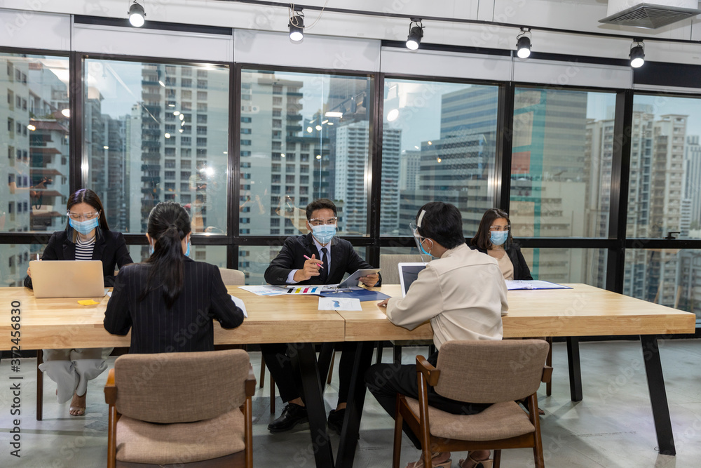 Business in new normal. Office workers wearing face mask and protection while having internal meeting for new business strategy or plan. Technology for new normal