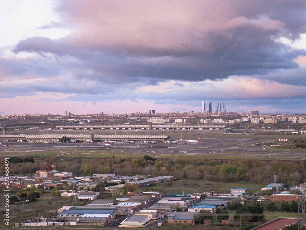 Spectacular cloudy sky at sunrise at Adolfo Suárez Madrid-Barajas Airport with the city of Madrid and the Cuatro Torres Business Area (CTBA), spectacular sky sunrise