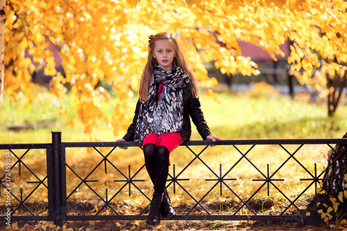 In autumn park walking little beautiful fashionable girl