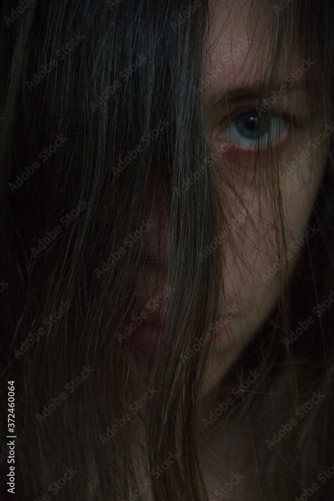 Dark photo where the hair is in focus. The girl's face is out of focus. Looking into the camera. Dark photo where the hair is in focus. The girl's face is out of focus. Looking into the camera.