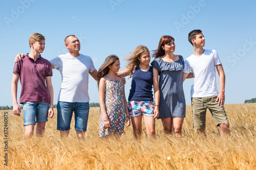 Obraz na plátně Multiple children family of farmers standing in line on yellow wheat field, teen