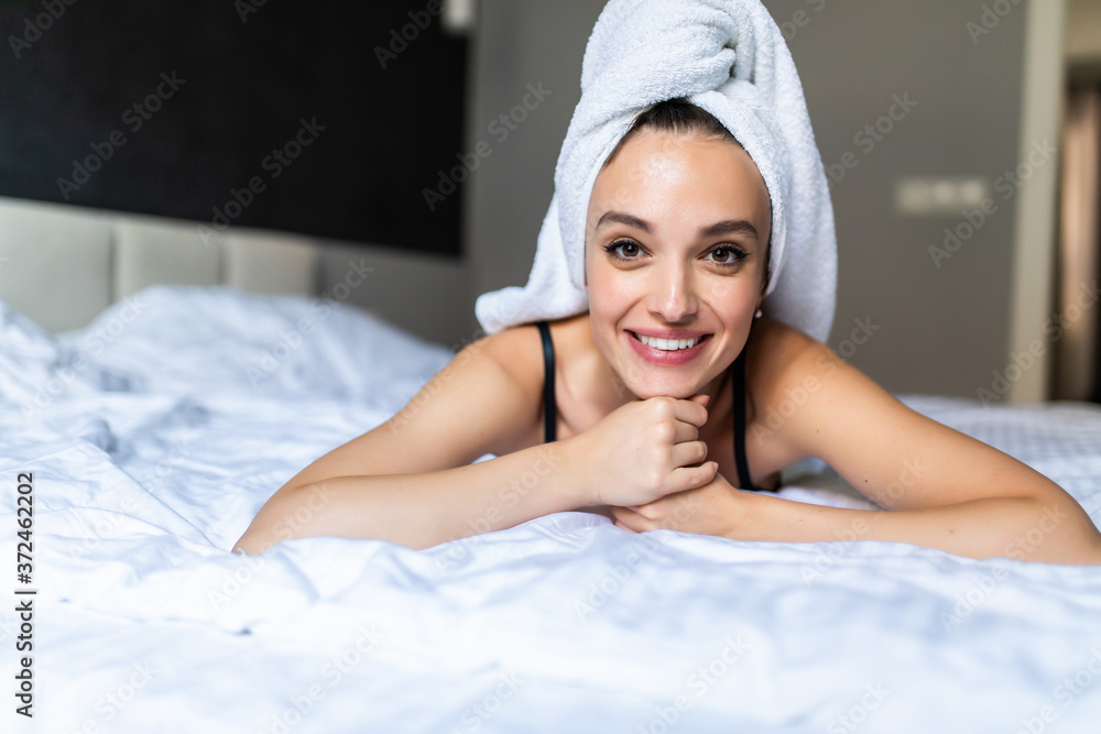 Young beautiful woman in towel and bathrobe laying on the bed and looking at the camera. Young beautiful woman in towel and bathrobe laying on the bed and looking at the camera.