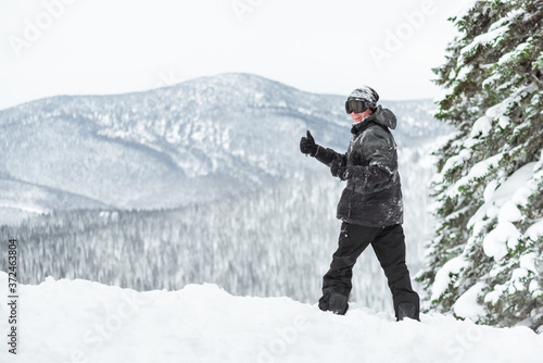 Snowboarder is standing on the winter slope and shows a thumbs up.