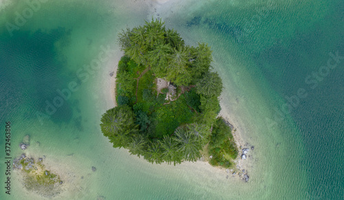 a view from a height of a mountain lake with emerald water and a small island with pine trees