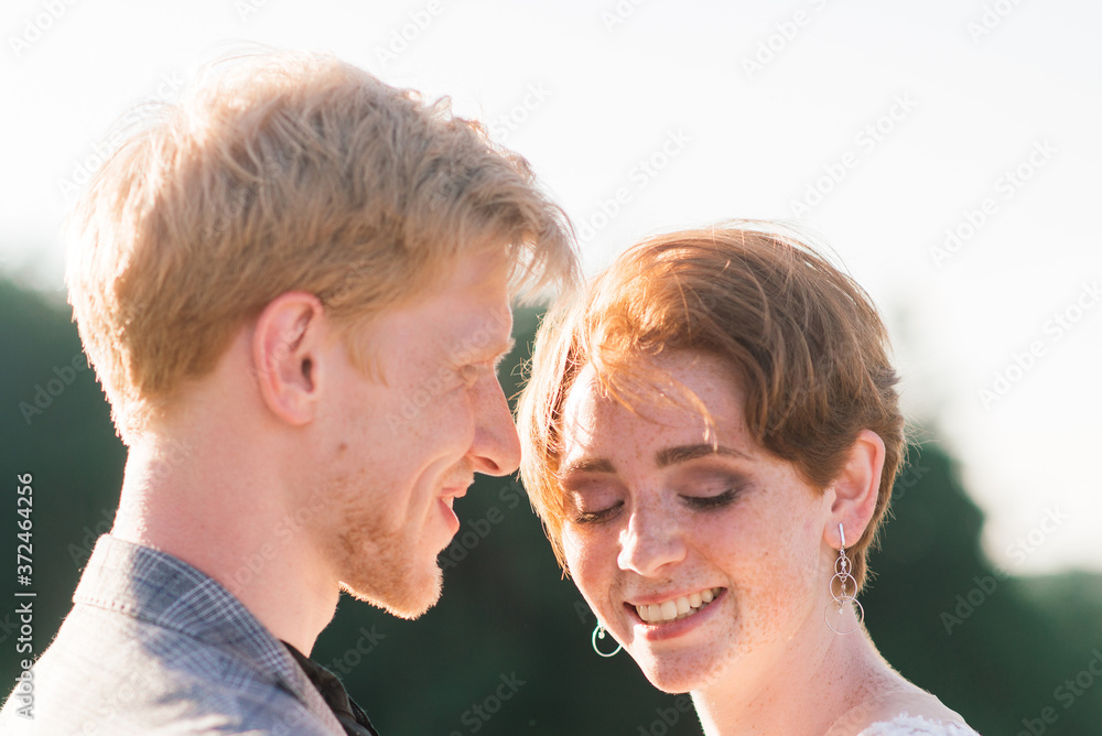 Nice redhead young just married happy couple kissing in the sunset outdoors