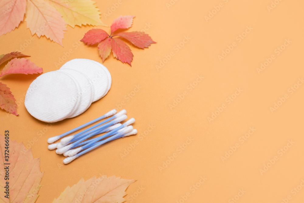 ear sticks and cotton pads on autumn background with red and yellow leaves ear sticks and cotton pads on autumn background with red and yellow leaves