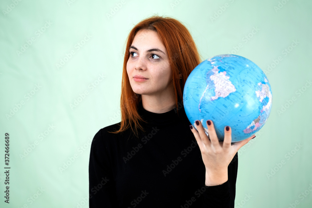 Portrait of a happy young woman holding geographic globe of the world in her hands. Travel destination and planet protection concept. Portrait of a happy young woman holding geographic globe of the world in her hands. Travel destination and planet protection concept.