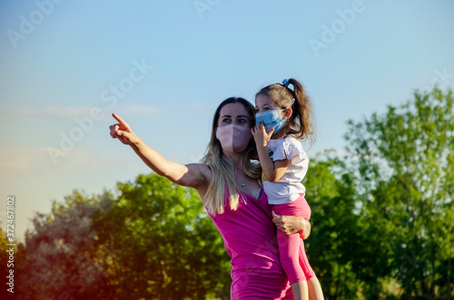 Mother teaches her little daughter. Caring, affectionate mother with her daughter in the meadow. Mother's love. Happy mom and daughter. Summer walk of mom and daughter wearing masks during quarantine 