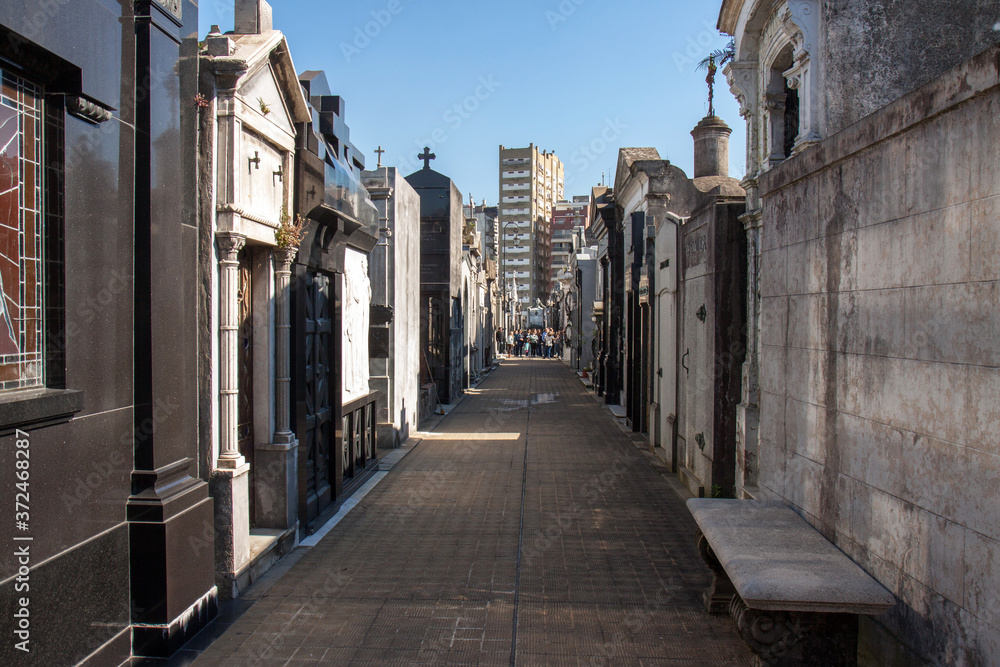 Buenos Aires, Argentina : alley of graves on Recoleta cemetery, on a clear day; in the backgroudn a group excursion